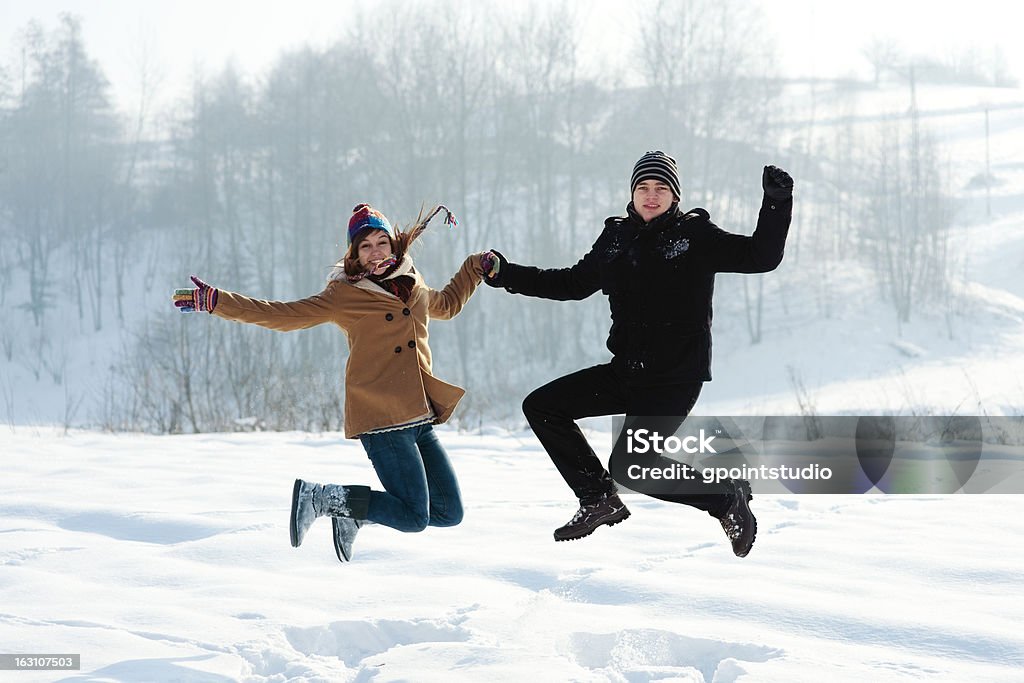 冬の楽しみ、屋外でのジャンプ若いカップル - 2人のロイヤリティフリーストックフォト