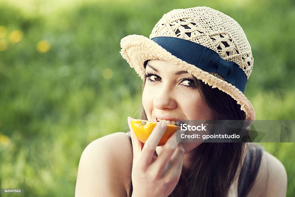 Linda mulher comer laranja sobre Prado - Royalty-free Adulto Foto de stock