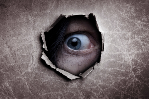 Female eye peeking through a hole 