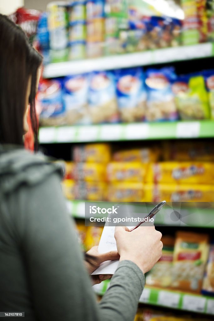 A person checks off their shopping list in a supermarket Woman holding a shopping list and a pen 20-29 Years Stock Photo