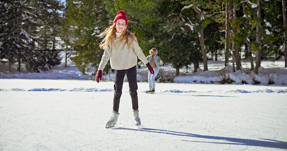 Portrait of smiling girl ice skating on frozen lake in winter.