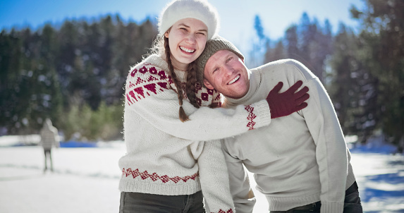 Portrait of smiling couple standing on frozen lake in winter.