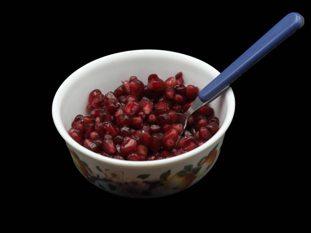 istock Red pomegranate seeds on a white porcelain plate. On black background 1631100481