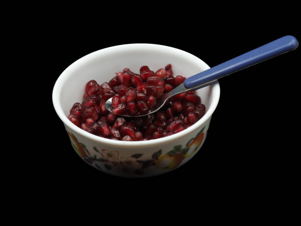 istock Red pomegranate seeds on a white porcelain plate. On black background 1631102180