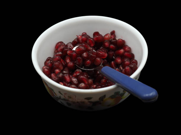 istock Red pomegranate seeds on a white porcelain plate. On black background 1631105516
