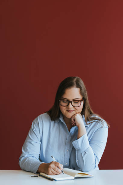 istock Smiling Caucasian Plus Size Businesswoman Sitting at the Office Desk, Writing Notes 1631114455