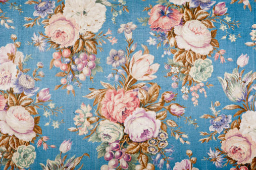 Antique floral fabric with clusters of pink, green and lavender flowers on a blue satin background..