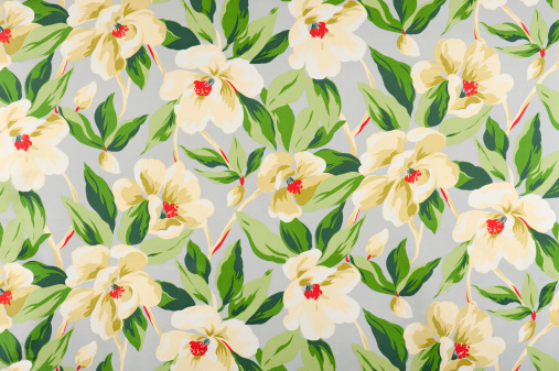 Antique floral fabric containing tropical yellow flowers on a grey background.