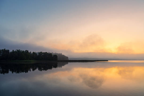 istock Sunrise with clouds and reflection at the lake Schaalsee in Seedorf, Germany 1631142559