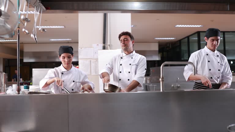 The Executive chef doing fried wok pan for delicious dish with his team in  restaurant kitchen.