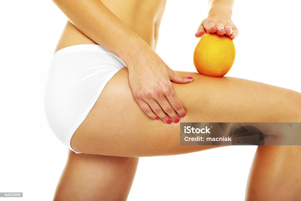 Cellulite treatment A picture of female legs and an orange over white background Adult Stock Photo