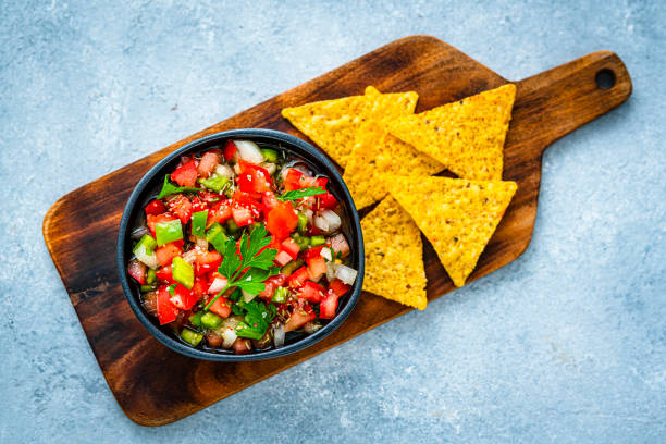 Mexican food: salsa pico de gallo and nacho chips shot from above on gray table