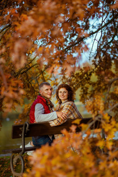 istock happy stylish couple in park sitting on bench 1631232548