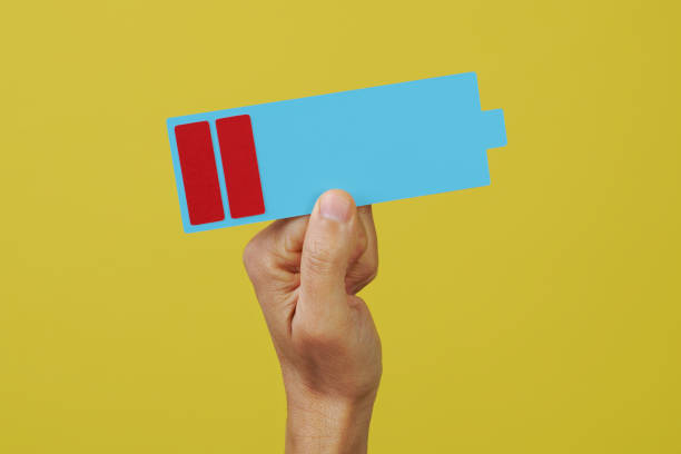 closeup of a man holding a depiction of a battery with a low charge level on a yellow background