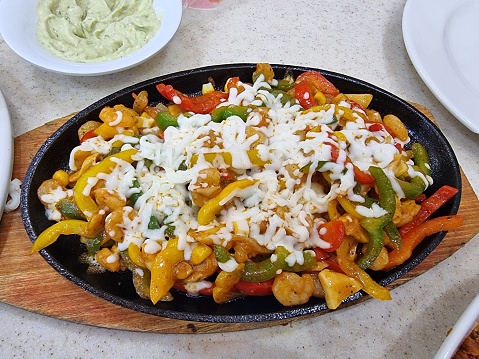 A fajita in Tex-Mex cuisine, is any stripped grilled meat, optionally served with stripped peppers and onions usually served on a flour or corn tortilla.