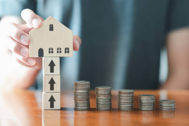 Businessman putting wooden mockup house with stack coins on desk. Saving money, bank deposits, interest collection and tax concept. Upward trend in business growth, financial management, funds. hombre de negocios poniendo maquetas de madera de la casa con monedas de pila en el escritorio. ahorro de dinero, depósitos bancarios, cobro de intereses y concepto fiscal. tendencia al alza en el crecimiento del negocio, gestión financiera, fondos