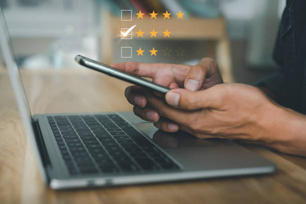 istock Virtual image scenario for evaluating customer satisfaction levels with mobile system. Ratings, reviews, survey responses. very happy, information. Man using mobile phone with laptop on wood desk in office 1631319874