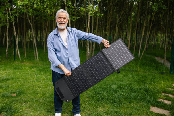 istock Mature man holding solar panel in garden. 1631347815