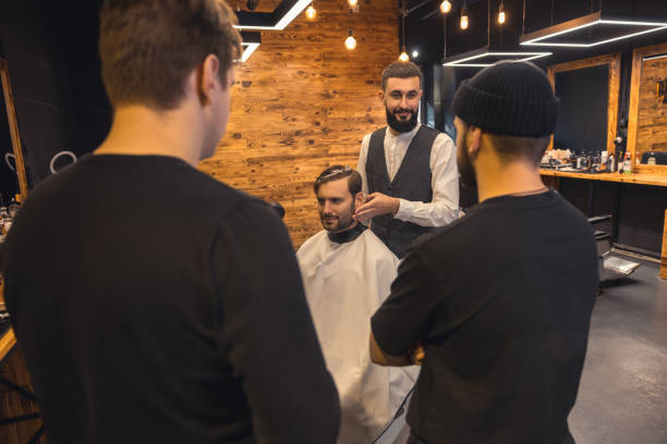 istock Barber teaches student to make men's hairstyles on model. 1631354548