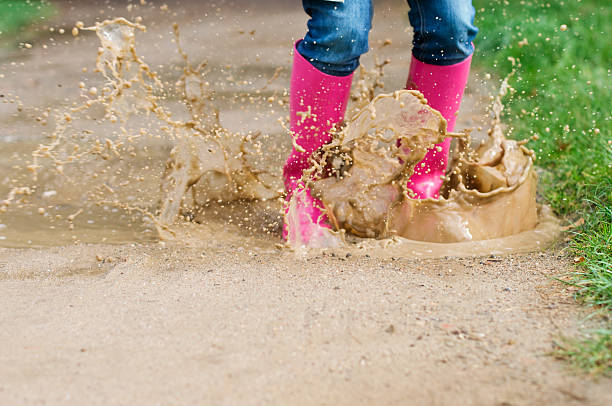 istock Young woman with rubber boots jumping in puddle 163136597