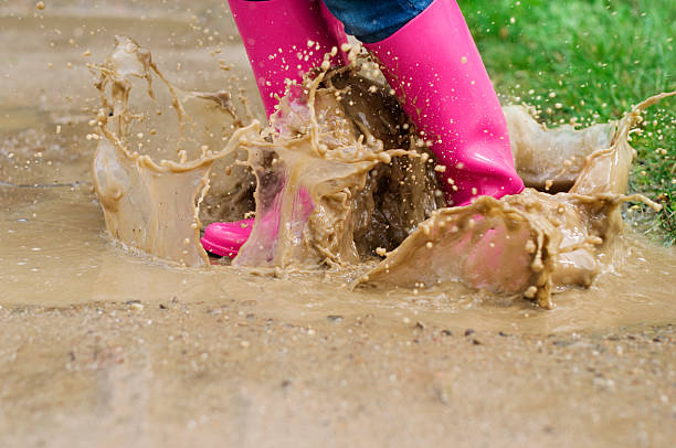 istock Young woman with rubber boots jumping in puddle 163136598