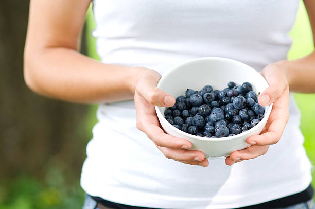 istock Young woman holding bowl filled blueberries 163136614