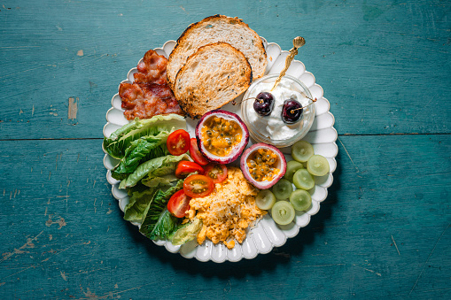 Breakfast toast, bacon, scrambled eggs with yogurt and grapes.