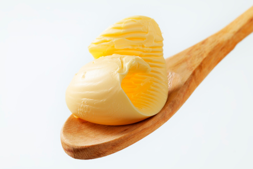 Butter curl on a wooden spoon isolated on white