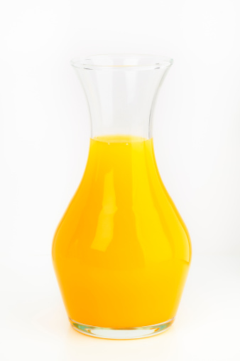 glass decanter of fresh orange juice on a white background