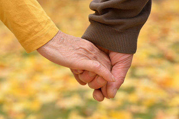 istock elderly couple holding hands 163139235