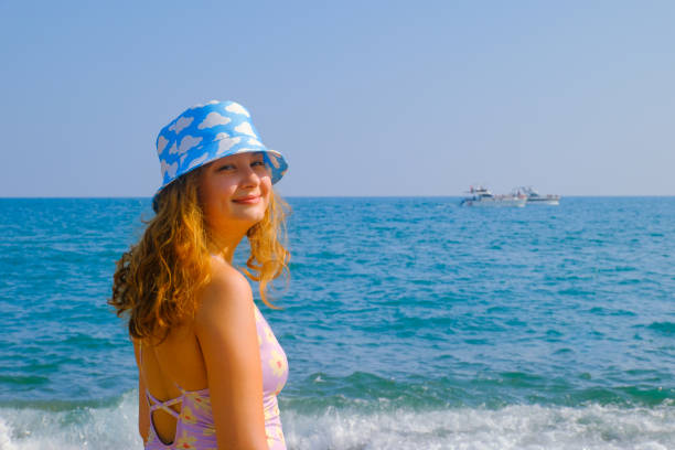 young woman on the beach with a cloud-patterned hat