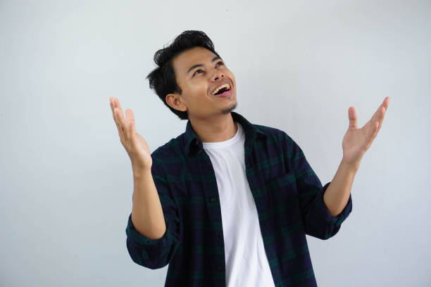 istock young asian man showing cheerful face expression and looking up with both hands open isolated on white background 1631425935
