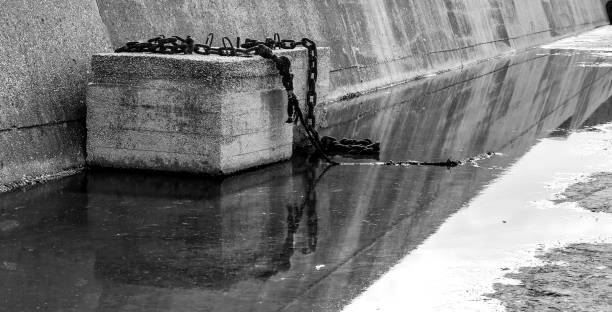 istock Concrete block with rusty chain on a puddle of stagnant water 1631439187