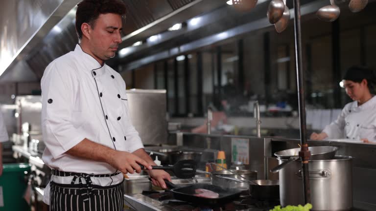 The Executive chef doing fried wok pan for delicious dish with his team in  restaurant kitchen.