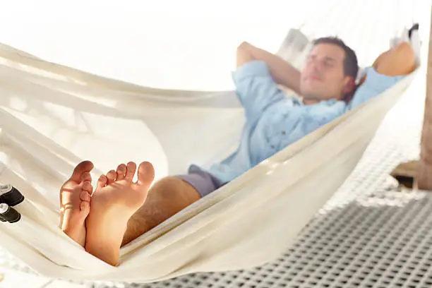 Young barefooted vacationer enjoys a nap in a hammock
