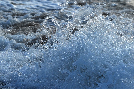 Sea wave rolls on the sandy shore forming white foam