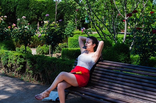 young woman , makes a tail in her hair sitting on a bench , to alleviate the high temperatures.