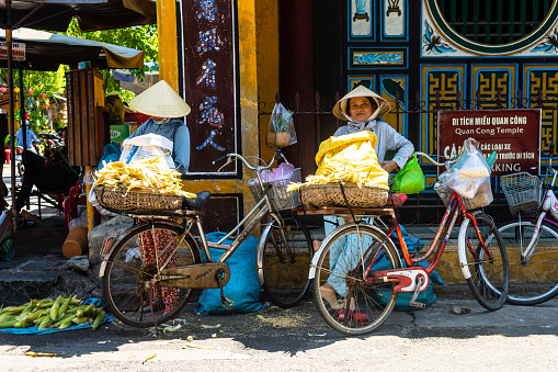 hoi an, vietnam. 16th june, 2023: vietnamese woman selling fresh fruit intheir wicker baskets at hoi an streets