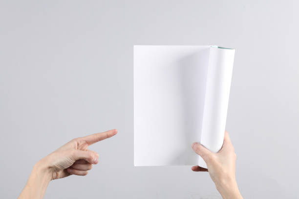 istock Female hands hold a blank magazine mockup with white pages on gray background 1631480980