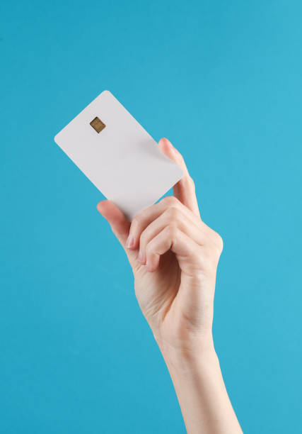 istock Woman's hand holds a white empty bank card with a chip on blue background. Layout, mockup, template for design 1631481520