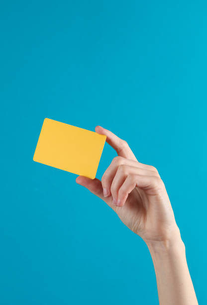 Woman's hand holds a golden empty bank card on a blue background stock photo