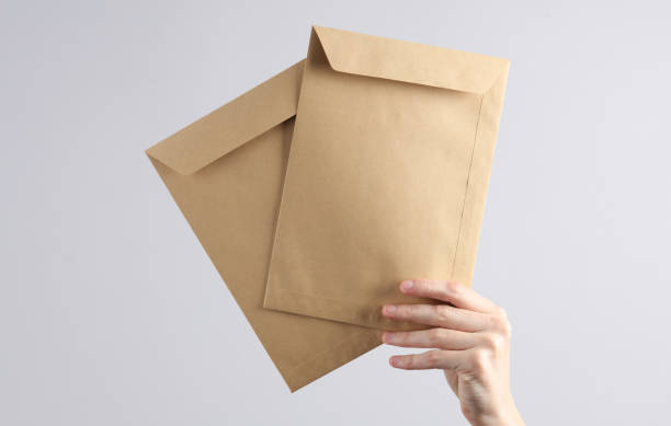 istock Two craft postal envelopes in  female hand on gray background 1631482668