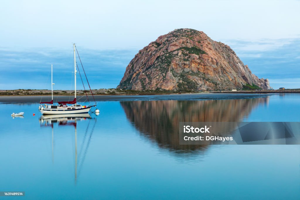 Morro Rock, Morro Bay California. Harbor with sailboat in foreground. Reflection on the water. Morning view of Morro Rock in Morro Bay, California. Harbor in foreground with sailboat. Mirror reflection on the water. Morro Bay Stock Photo Morro Rock, Morro Bay California. Harbor with sailboat in foreground. Reflection on the water. Morning view of Morro Rock in Morro Bay, California. Harbor in foreground with sailboat. Mirror reflection on the water. Morro Bay Stock Photo