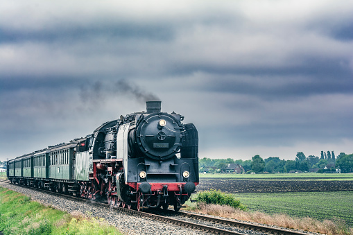 Steam train runs on the tracks in the countryside.
