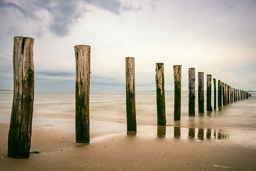 Beach poles in the sea on a cloudy day at the North Sea Beach in South Holland.