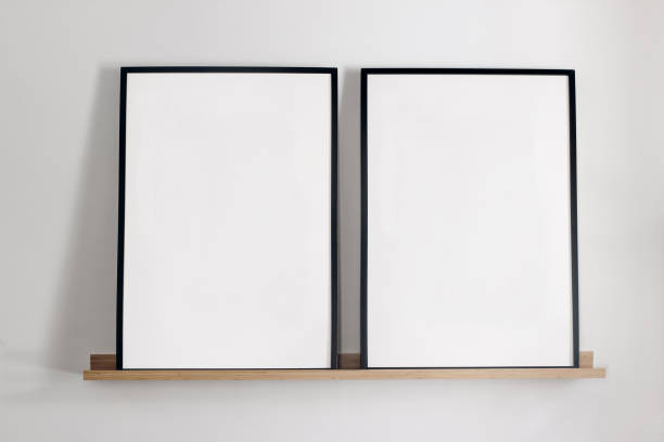 istock Artistic mockups template. Two black vertical picture frames on bamboo wooden shelf. White wall background. Posters at home, minimal Scandinavian design, no people. Elegant apartment concept. 1631514756