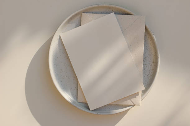 Summer minimal wedding stationery. Blank vertical greeting card mockup with beige envelope, invitation. Ceramic dessert plate in golden sunlight. Table background with shadows overlay. Flatlay, top Summer minimal wedding stationery. Blank vertical greeting card mockup with beige envelope, invitation. Ceramic dessert plate in golden sunlight. Table background with shadows overlay, flatlay, top restaurant table layout stock pictures, royalty-free photos & images