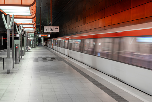 High speed train in motion on the railway station at night. Blurred red modern intercity passenger train, railway platform, buildings, city lights. Railroad in Vienna, Austria. Railway transportation