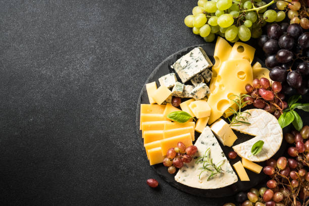 istock Cheese platter with craft cheese assortment and grape at black background. 1631525849