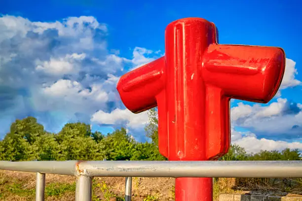 Styled Red Fire Cock Hydrant Against of Blue Sky On The Street Of City. Horizontal Image